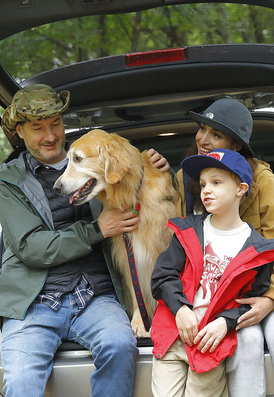 Familie mit Hund sitzt im Kofferraum eines Subaru